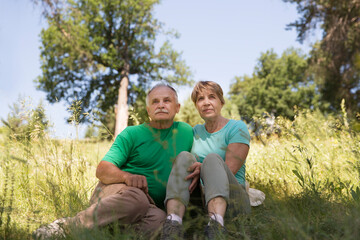 Naklejka na ściany i meble Portrait of attractive vibrant senior couple embracing in summer day outdoors. Staycations, hyper-local travel, family outing, getaway, natural environment