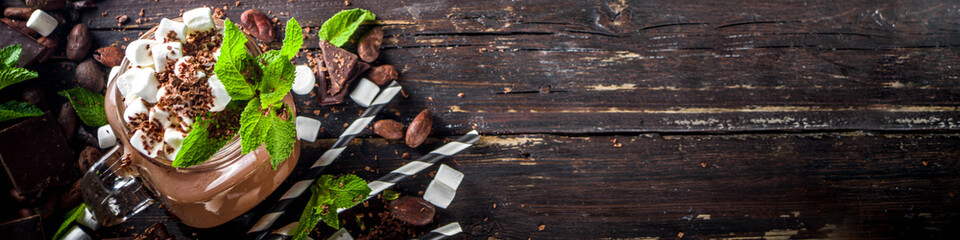Chocolate milk shake with sauce, marshmallows and grated chocolate, decorated with mint. On old...