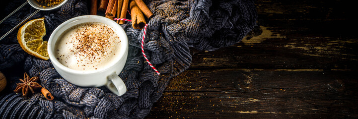 Autumn sweet hot drink, Chai Buttered Rum, Pumpkin Pie or Pumpkin Spice Coffee Latte. Cozy autumn background with traditional latte cup, spices and old sweater, on rustic wooden background