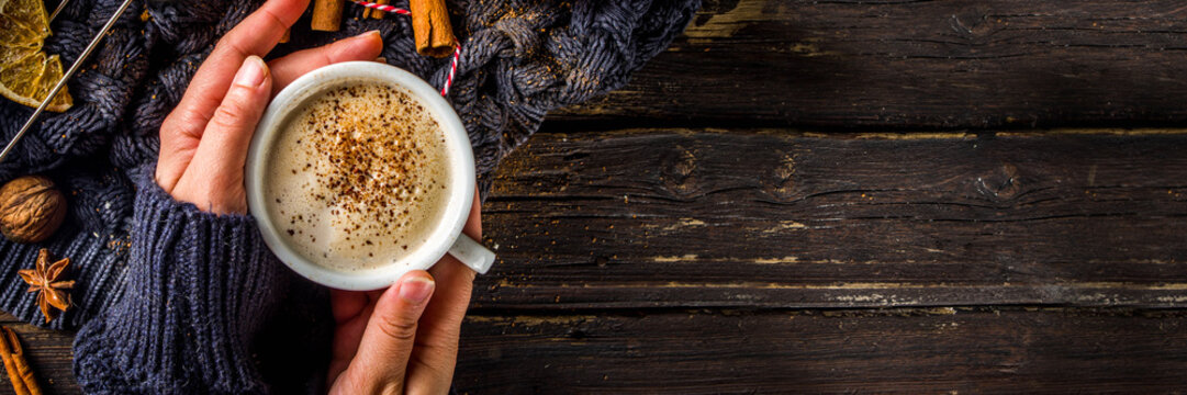 Autumn sweet hot drink, Chai Buttered Rum, Pumpkin Pie or Pumpkin Spice Coffee Latte. Cozy autumn background. Girl hold traditional latte cup in hands, on rustic wooden background