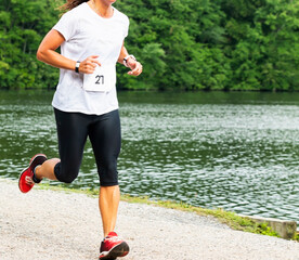 Female running a trail 10K race passing a lake