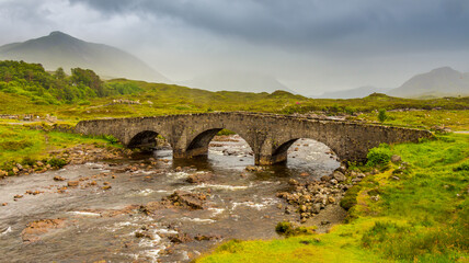 Fototapeta na wymiar Sligachan bridge by the River Sligachan, on a overcast summers morning on the Isle of Skye, Scotland, with the Cuillin Mountains in the background.