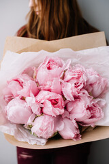 Very nice young woman holding big and beautiful mono bouquet of fresh tender pink peonies, cropped...