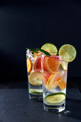Infused water with grapefruit, orange, lemon, lime and ice on dark background