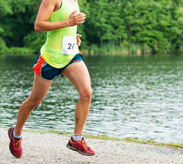 Runner running a race on a trail next to a lake