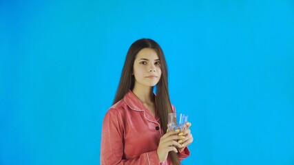 Caucasian teen female girl drinking glass of water. Young woman drinking water from glass on blue background in studio