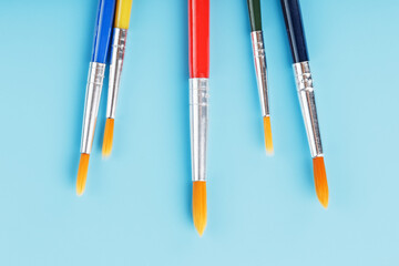 Brushes of different colors for drawing, creativity and art on a blue background.