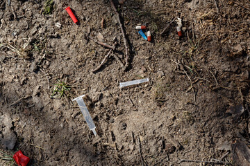 a used broken medical needle, syringe, cap and tablets lie on the ground in a city Park