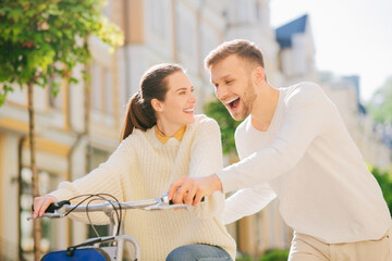 Fototapeta premium Man teaching a joyful woman riding bike