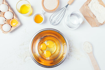 Top view raw eggs in metal bowl next to other ingredients