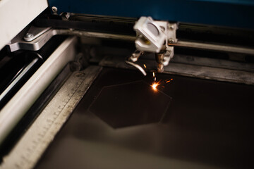 Industrial laser engraving hexagon shaped geometric figure with sparks bursting, close up view