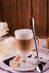 coffee latte  with cream and foam with a spoon in a tall glass on a background of cake a wooden background
Chocolate Milk