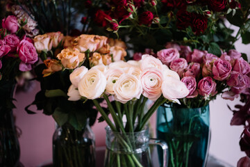 Fresh delivery at the florist shop: vases with blossoming roses, eucalyptus, carnations, ranunculus flowers 