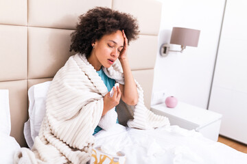 Ill african young woman covered with blanket blowing running nose got fever caught cold sneezing in...