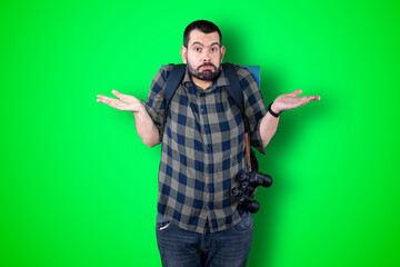 Closeup photo of young handsome traveler man isolated on green studio background dressed casually, looking bored, exhausted and disappointed, feeling helpless and upset facing problems