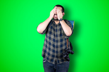 I'm afraid. Fright. Portrait of the scared traveler man. Business man standing isolated on trendy green studio background. Male half-length portrait. Human emotions, facial expression concept