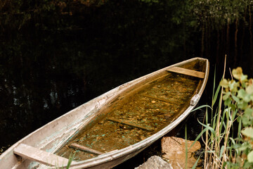 Old sunken wooden boat on lake in thicket of grass