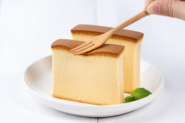 Castella (kasutera) - Beautiful delicious Japanese sliced sponge cake food on white plate over rustic white wooden table, close up, copy space design concept.