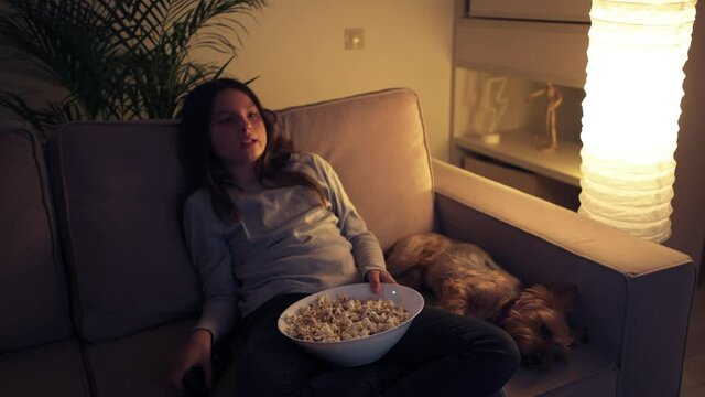 The girl turns off the TV remote control. A girl is sitting with her dog