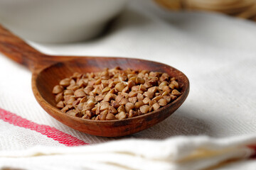 Wooden spoon with uncooked buckwheat close up