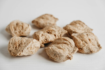 Raw dehydrated soy meat or soya chunks on a white wooden background. Copy, empty space for text