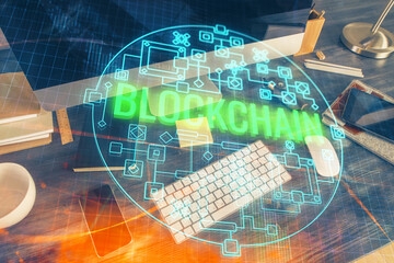 Double exposure of blockchain and crypto economy theme hologram and table with computer background. Concept of bitcoin cryptocurrency.