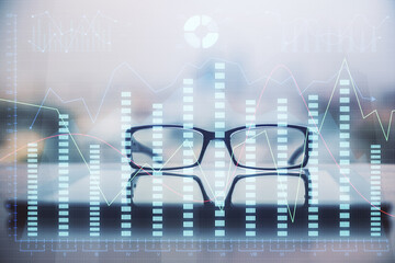 Financial graph hologram with glasses on the table background. Concept of business. Double exposure.