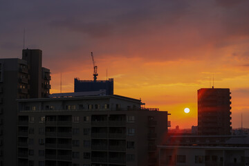 街のマンションと遠く沈む太陽の風景