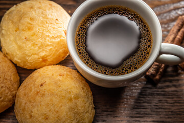 Café preto dentro de xícara branca e dois pães de queijo.