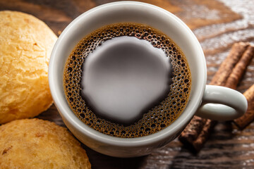Xícara branca com café e pão de queijo.