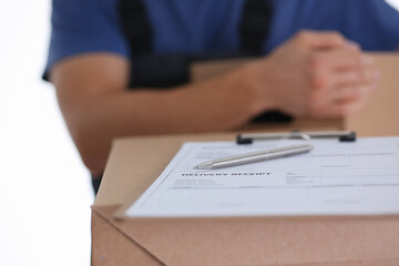 Close up of deliver man standing by cardboard box with pen and delivery receipt