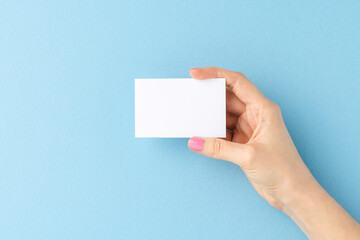 Woman’s hand holding business card on blue background. Mockup. Close up