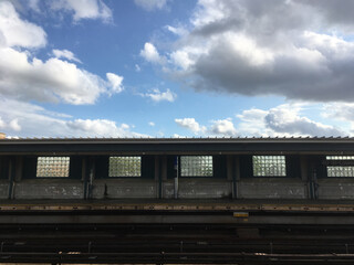 Empty elevated subway platform in New York City. Vacant overground subway station on a bright day with blue skies. Empty train station in Queens New York, room for copy.
