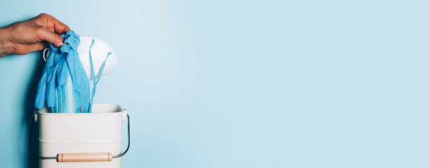 Pandemic is over concept. Quarantine end. Stop Coronavirus. Hand throws medical masks to trash bin...