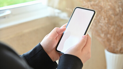Close up image of female hands using smartphone with blurred background.