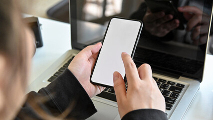 woman using smart phone with laptop in office and hand holding smart phone empty screen.