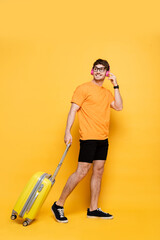 happy handsome man in headphones walking with travel bag on yellow