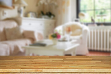 Brown empty wooden table top with blurred living room that can see garden background. Light wood with blurry in living room interior.
