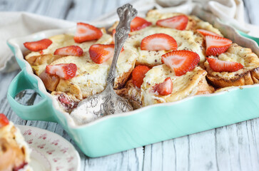 Strawberry cheesecake French toast casserole with missing piece. Made with cream cheese and strawberries. Selective focus with blurred background.