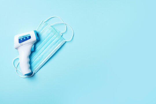 Digital medical infrared non contact thermometer gun for measuring temperature on blue background for coronavirus COVID-19 testing. Medicine concept. Quarantine pandemic. Stay safe - Powered by Adobe