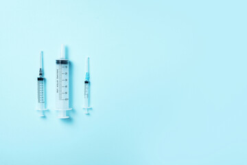Syringes of different size on blue background. Injections and vaccination concept. Health protection medicine equipment during quarantine Coronavirus pandemic. Top view. Copy space