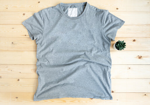 Gray male t shirt mock up flat lay on wooden background. Top front view