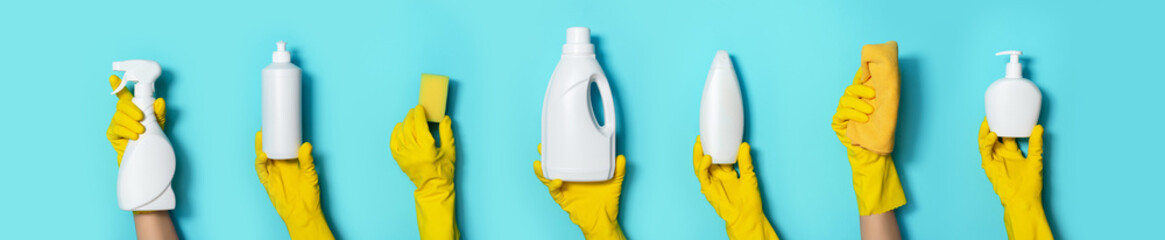 Hands in gloves holding detergent bottles on blue background. Banner with copy space. Chemical...