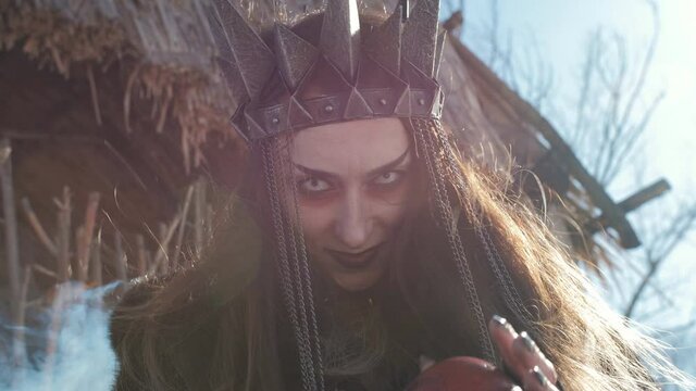The witch holds out his hand with a red Apple at the forbidden fruit, close-up.