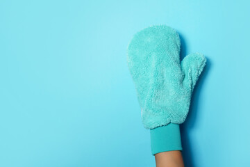 Hand in glove holding microfiber cleaning cloth, cleaning mitten on blue background. Copy space. Cleaning service concept. Spring general or regular clean up. Commercial cleaning company concept.