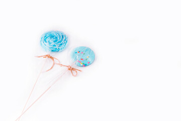 Sweets set: hand made blue lollipop and meringue on wooden stick on white background. The concept of sweets for the holidays, birthday. Candy bar. Flat lay. Copy space for text.