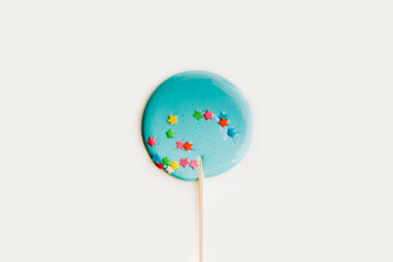Hand made blue lollipop on wooden stick on white background. The concept of sweets for the holidays, birthday. Candy bar. Flat lay. Copy space for text