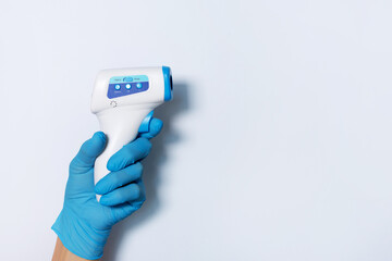 Hand in medical glove with digital infrared non contact thermometer gun for measuring temperature...