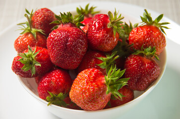 Strawberries in a white plate on the table.