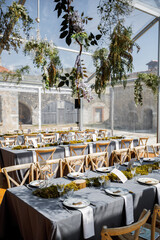wedding table decorated by plates, knives and forks, candle, moss and greenery
